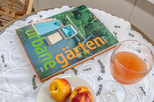 a table with a book and a plate of apples and a drink at Ferienapartments Pirna in Pirna