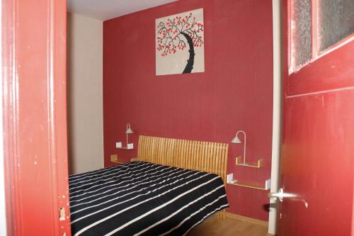 a bedroom with a red wall with a tree painting at Casa Seblina in Ostend