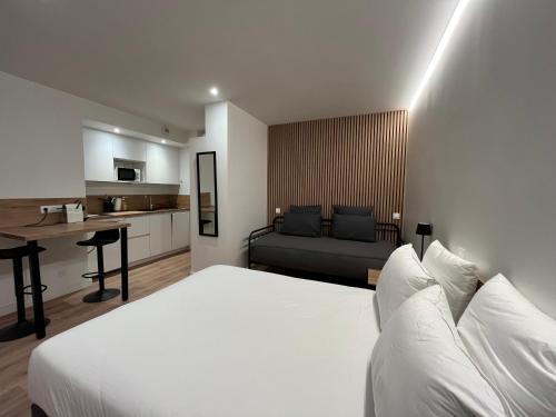 a bedroom with a white bed and a kitchen at Studio Hôtel-Restaurant LTB La Table Basque in Biarritz