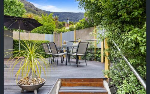 a patio with a table and chairs and an umbrella at Luxury Spa Villa - Mountain Views Right in Town! in Halls Gap