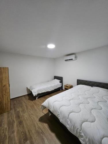 a white bedroom with two beds and a wooden floor at Montana apartman in Han Pijesak