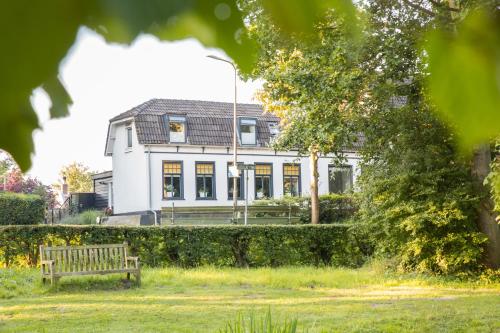 a white house with a bench in front of it at B&B Ons Dijkhuisje in Schuddebeurs