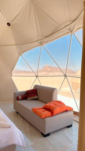 a couch in a tent with a view of the desert at MARS MIRROR BUBBLE lUXURY CAMP in Wadi Rum