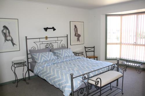 a bedroom with a bed with a blue and white comforter at Maslin Beach House in Maslin Beach