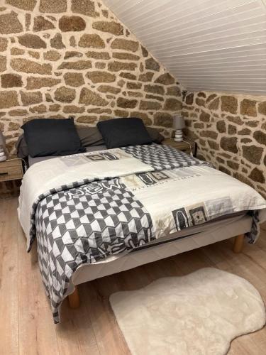 a bed in a room with a stone wall at Maison en pierre pour 6-jardin &animaux bienvenus in Languidic