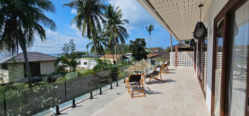ein Balkon mit Stühlen, einem Zaun und Palmen in der Unterkunft Villa Trident Srithanu Koh Phangan 2 min of Zen Beach in Ko Kong Nui