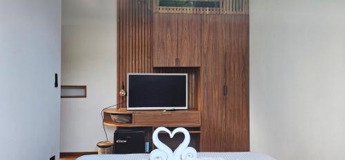 ein Zimmer mit Fernseher und Bett mit weißen Schuhen in der Unterkunft Villa Trident Srithanu Koh Phangan 2 min of Zen Beach in Ko Kong Nui