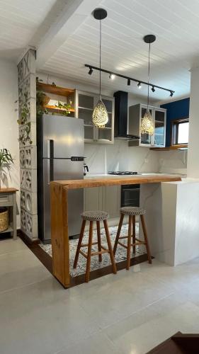 a kitchen with a counter with stools and a refrigerator at Casa Aroeira Sahy in Barra do Sahy