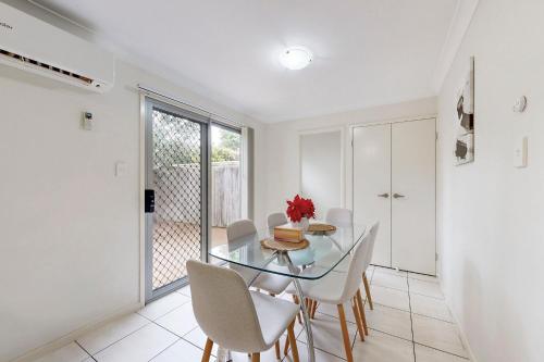 a dining room with a glass table and white chairs at Homely & Welcoming in Mango Hill in North Lakes