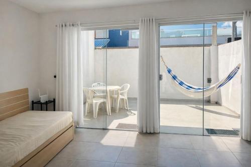 a bedroom with a bed and a balcony with a table at Apartamento do Peró in Cabo Frio