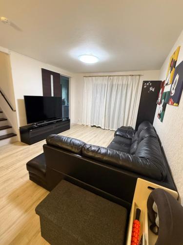 a living room with a leather couch and a flat screen tv at Free Parking Namba south Villa 4 rooms 120m2 in Osaka