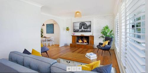 a living room with a couch and a fireplace at 47 Murrah - Lux 3 bed home, walk to everything - Pet friendly in Bermagui