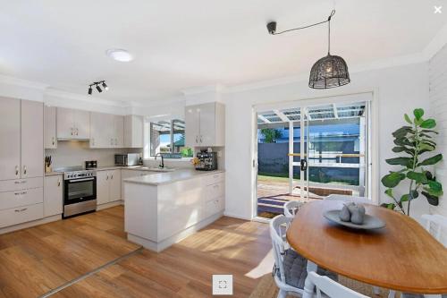 a kitchen with a wooden table and a dining room at 47 Murrah - Lux 3 bed home, walk to everything - Pet friendly in Bermagui