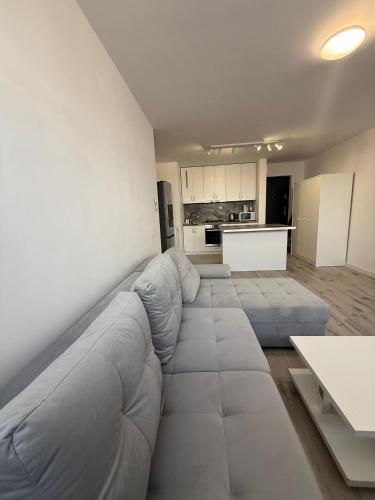 a living room with a large couch and a kitchen at Apartament Centrum nr 8 in Radom