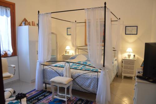 a bedroom with a canopy bed with curtains and a chair at B&B Vicolo del Chiostro in Aci SantʼAntonio