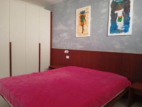 a bedroom with a pink bed with two pictures on the wall at Sol Lazareto Mindelo in Prainha