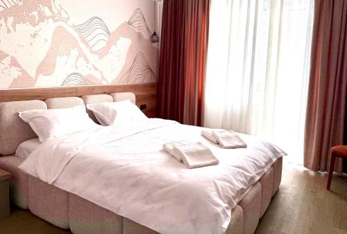 a bedroom with a white bed with two towels on it at Boutique Hotel Pui de Urs Fundata in Ciocanu