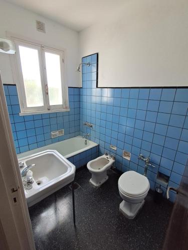 a blue tiled bathroom with a toilet and a sink at Amplio dpto Miramar centro y playa in Miramar