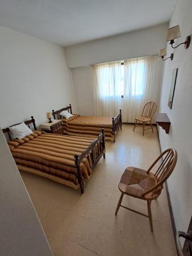 a large room with three beds and two chairs at Amplio dpto Miramar centro y playa in Miramar