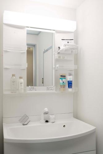 a white bathroom with a sink and a mirror at KURIHAMA Base 102 in Kubiri