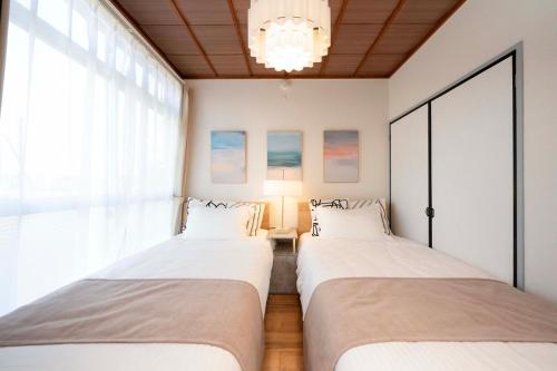 two beds sitting in a room with a window at KURIHAMA Base 102 in Kubiri