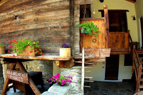 ein Holzgebäude mit Topfpflanzen darauf in der Unterkunft B&B A Pankeo in Valtournenche