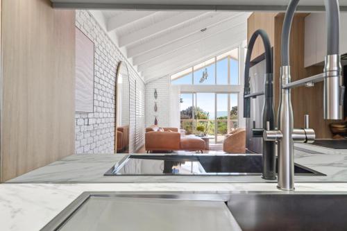 a kitchen with a sink and a living room at Apollo Bay Gone Surfin in Apollo Bay