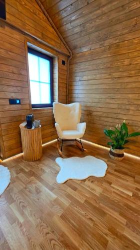 a room with a chair and a window and wooden walls at Casuta de la munte in Sărişor