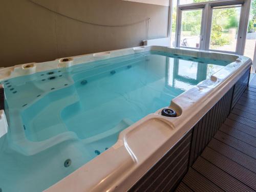 a large hot tub with blue water in a room at Het Grootenhuis in Olst