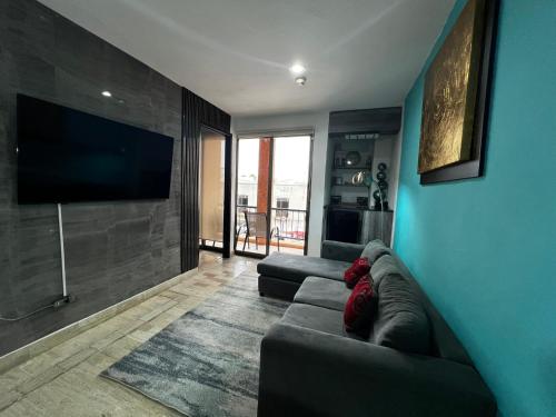 a living room with a couch and a flat screen tv at Tu Depa en el Paraiso Cancún in Cancún