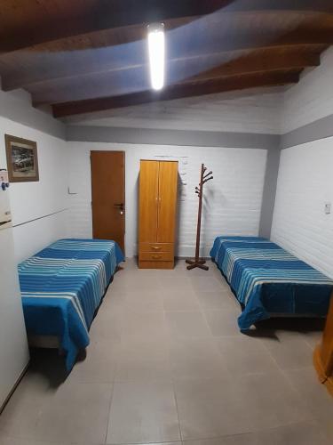 a room with two beds and a wooden cabinet at Departamento b privado cerca arena Maipú p4 personas cochera in Maipú