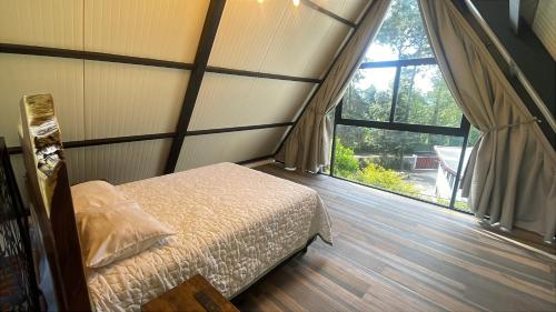 a bedroom with a bed and a large window at Cabañas Los Angeles in Valle de Bravo