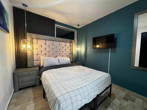 a bedroom with a bed and a blue wall at Tu Depa en el Paraiso Cancún in Cancún