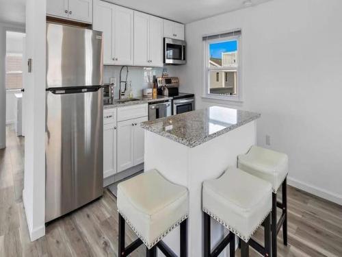 a kitchen with a bar with stools and a refrigerator at Lbi - Ship Bottom, Duplex Available For Summer 2026 in Ship Bottom