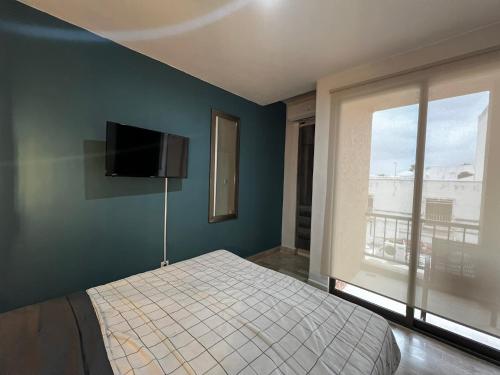 a bedroom with a bed and a tv on the wall at Tu Depa en el Paraiso Cancún in Cancún