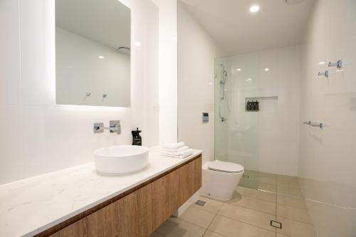 a white bathroom with a sink and a shower at X Kirra Apartments in Gold Coast