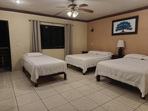 a room with two beds and a ceiling fan at Hotel Tropigalas in Tampamachoco