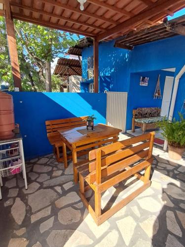 a patio with two benches and a table and a blue wall at Pousada Odoyá Beach - Casal in Conde