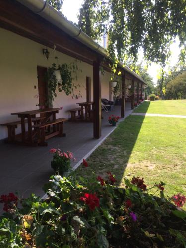a patio with picnic tables and flowers in a yard at Vadaspuszta Vendeghaz in Csatka
