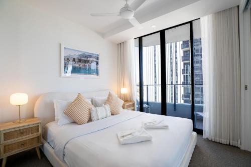 a white bedroom with a large bed and a large window at X Kirra Apartments in Gold Coast