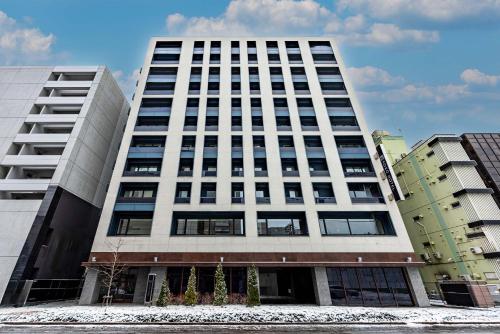 a tall white building with many windows at KOKO HOTEL Sapporo Susukino - formerly Hotel Wing International Sapporo Susukino in Sapporo