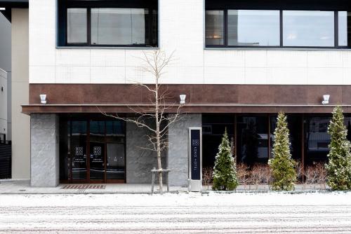 a building with a tree in front of it at KOKO HOTEL Sapporo Susukino - formerly Hotel Wing International Sapporo Susukino in Sapporo