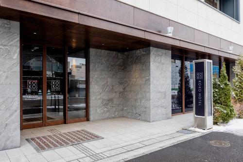 a building with glass doors on the side of it at KOKO HOTEL Sapporo Susukino - formerly Hotel Wing International Sapporo Susukino in Sapporo