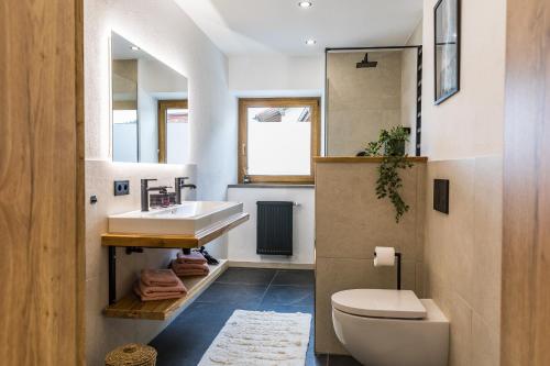 a bathroom with a sink and a toilet and a mirror at Hotel Garni Edelweiß in Siegsdorf
