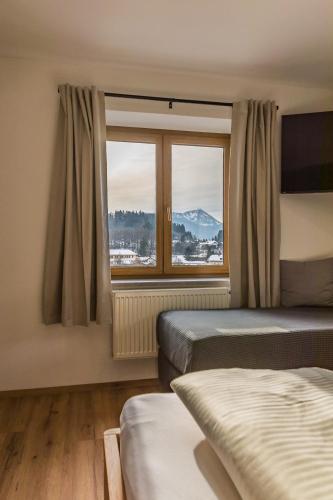 a bedroom with two beds and a large window at Hotel Garni Edelweiß in Siegsdorf