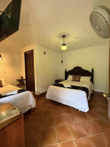 a bedroom with two beds and a fan at Hotel Makani in Panajachel