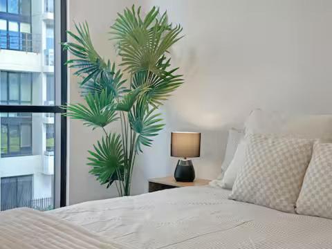a bedroom with a bed and a palm tree at Prime Location for an Event in Olympic Park in Sydney