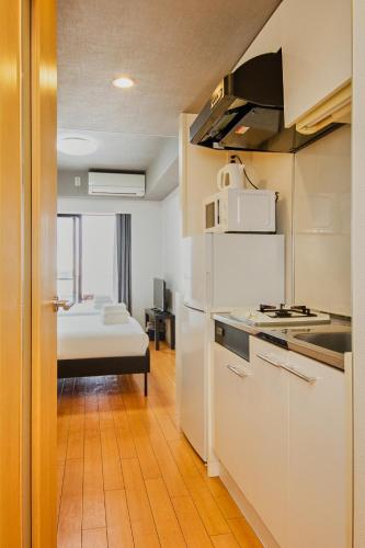 a kitchen with white appliances and a room with a bed at Shinjuku-IEE in Tokyo