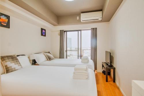 a hotel room with two beds and a television at Shinjuku-IEE in Tokyo