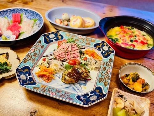 a table with plates of food and bowls of food at 星降る別邸WANASA in Kannoura